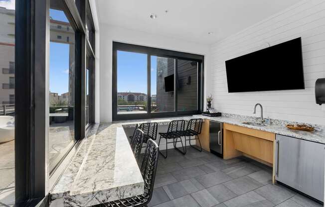 A modern kitchen with a marble countertop and a large window.