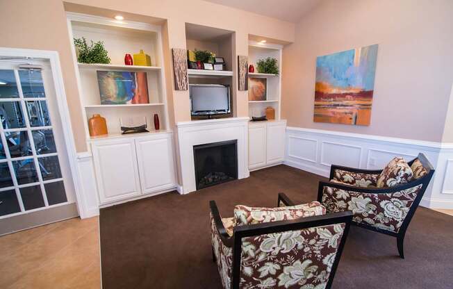 A living room with a fireplace and two chairs.