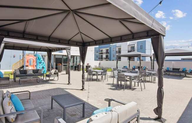 A patio area with tables and chairs under a large umbrella.