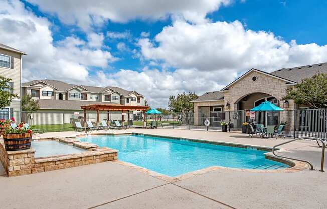 A swimming pool surrounded by a fence and a building in the background.