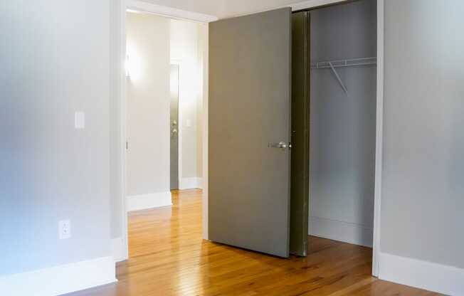 an empty living room with wood floors and a closet