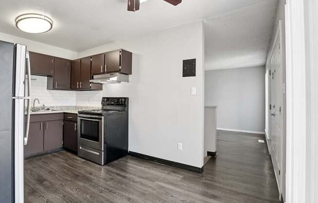 A kitchen with brown cabinets and a black fridge.