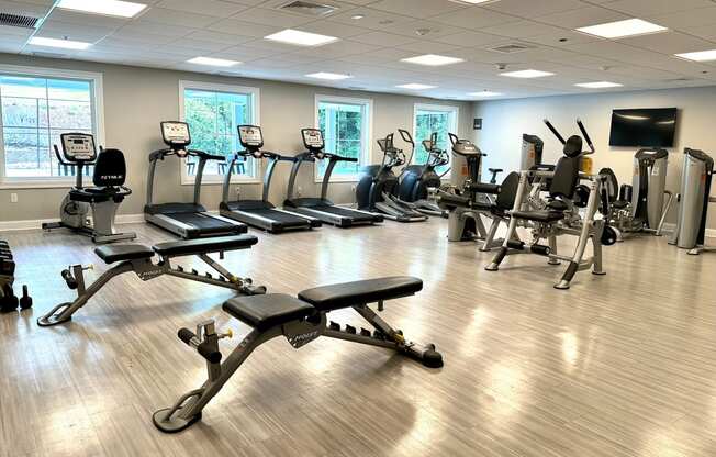 a large fitness room with cardio equipment and a flat screen tv