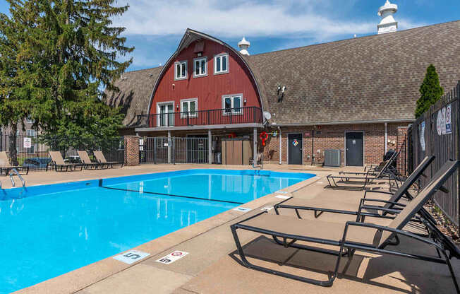 A large swimming pool in front of a red barn.