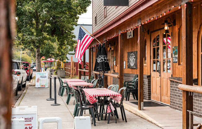 A restaurant with tables and chairs outside with an American flag hanging on the wall.