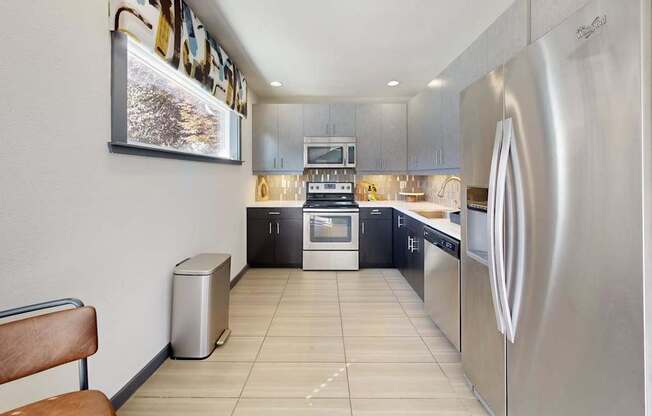 A modern kitchen with stainless steel appliances and a wooden bench.
