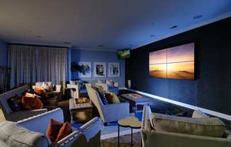 A living room with a large screen on the wall and a couch.
