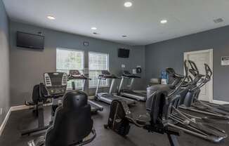 A gym with treadmills, exercise bikes, and a television.