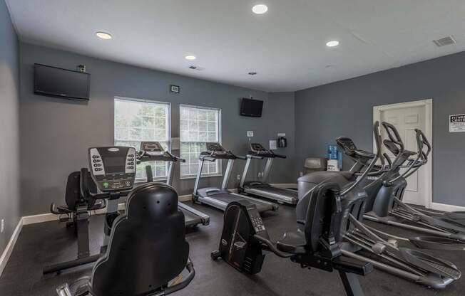 A gym with treadmills, exercise bikes, and a television.