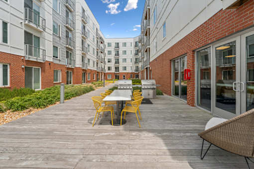 A patio with a table and chairs is surrounded by apartment buildings at The Waterford At Rocketts Landing Apartments, PRG Real Estate, Richmond, Virginia