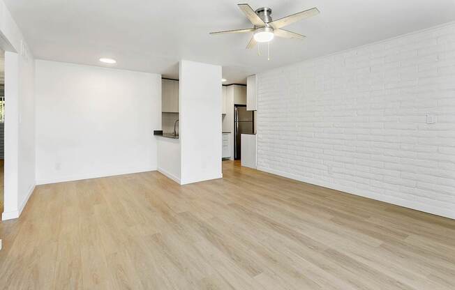 A room with a ceiling fan and wooden flooring.