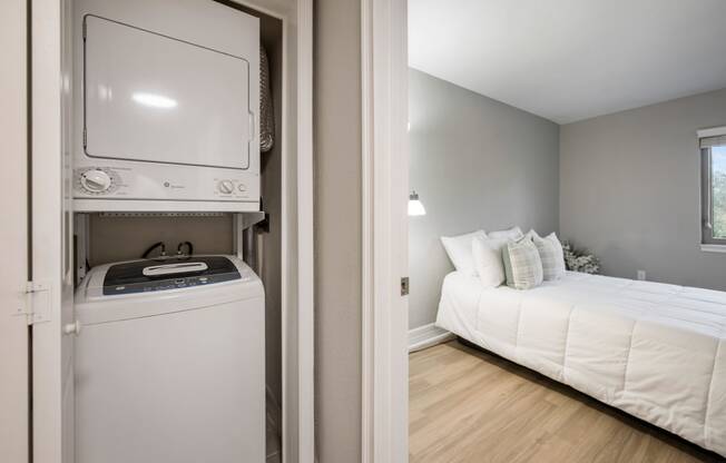 a small bedroom with a bed and a washer and dryer in a room