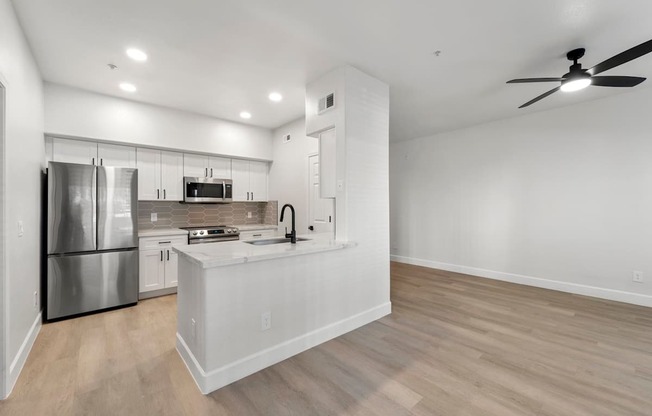 A modern kitchen with a stainless steel refrigerator and a wooden floor.