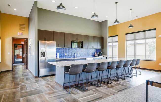 A kitchen in the clubhouse with an oversized island and several barstools.