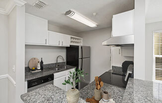 Model Kitchen with White Cabinets and Wood-Style Flooring at Shadow Ridge Apartments in Riverdale, GA.