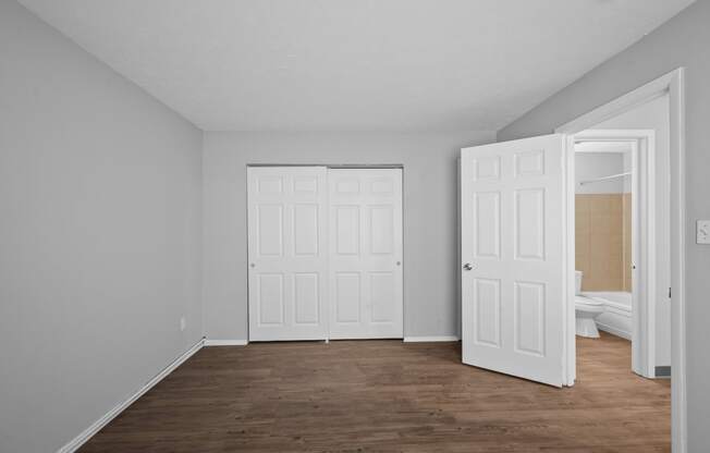 an empty room with white walls and a door to a bedroom