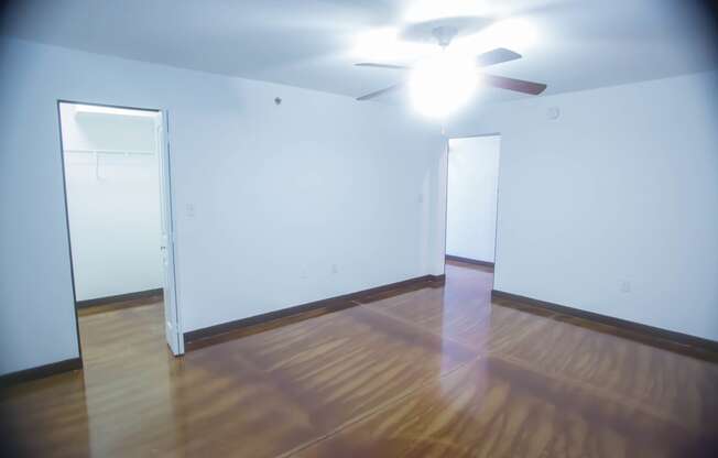 A room with a ceiling fan and wooden floors.