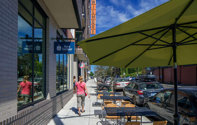 a woman walking down a sidewalk in front of a restaurant