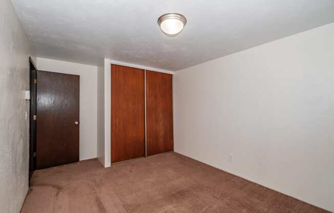 a bedroom with a carpeted floor and a door to a closet