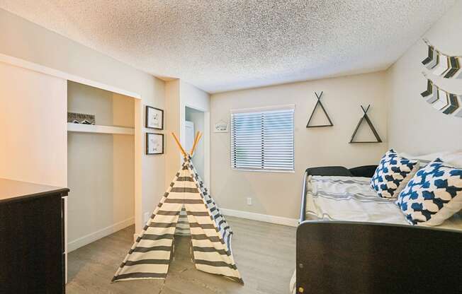 A room with a bed, a dresser, and a striped rug.