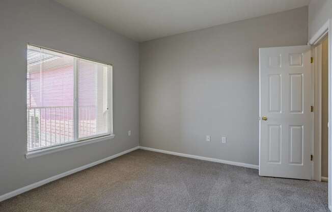 an empty bedroom with a large window and a white door at Stetson Meadows Apartments, Colorado