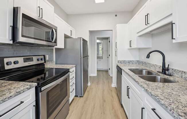 A kitchen with white cabinets and granite countertops.