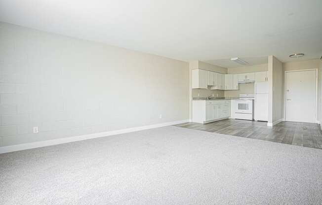 an empty living room and kitchen with white appliances