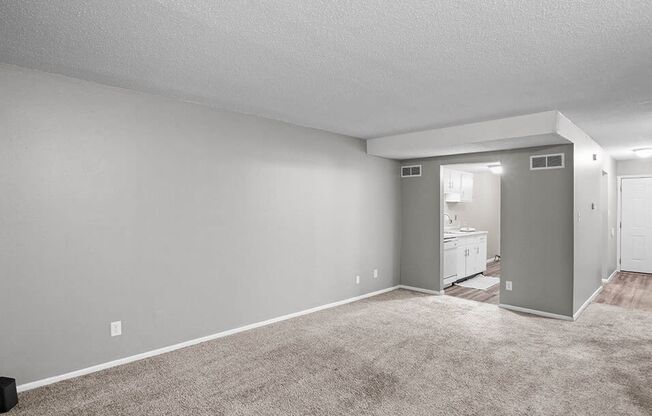 an empty living room with carpeting and a white bathroom