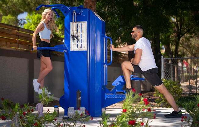 A woman in a white top and black shorts is jumping into a blue water fountain.