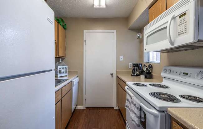 A white refrigerator is in a kitchen with a white door and a white stove.
