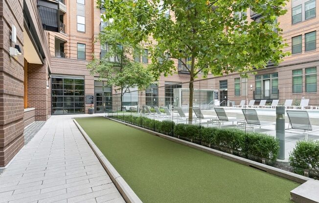 a courtyard with grass and chairs in front of a building