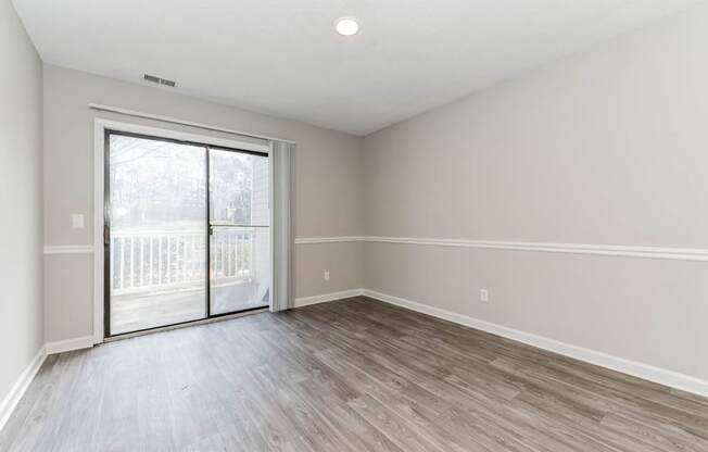 A room with a sliding glass door and wood flooring.
