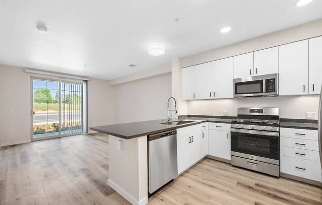 an empty kitchen with white cabinets and stainless steel appliances