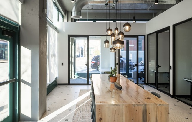 a long wooden table in a lobby with glass doors at The Draper, St Louis, 63103