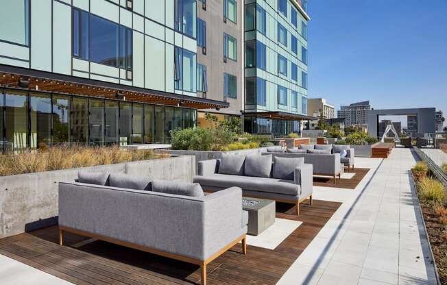 A patio with grey couches and wooden tables.