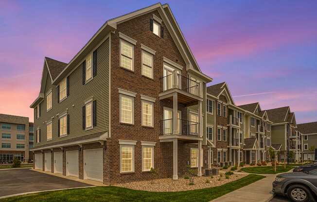 an exterior view of an apartment complex with a sunset in the background at Meadowbrooke Apartment Homes, Grand Rapids, Michigan