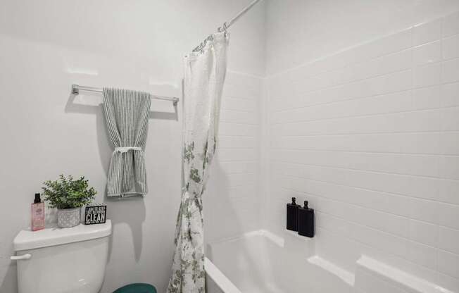 A white bathroom with a white toilet and a white bathtub.