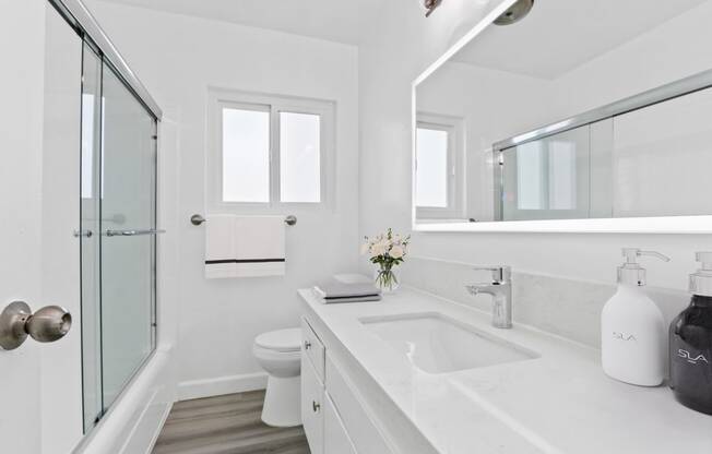 a white bathroom with a sink and a shower