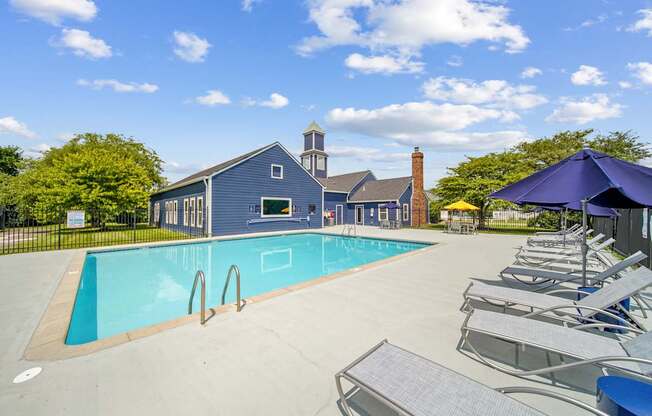 A pool with a blue umbrella and chairs.
