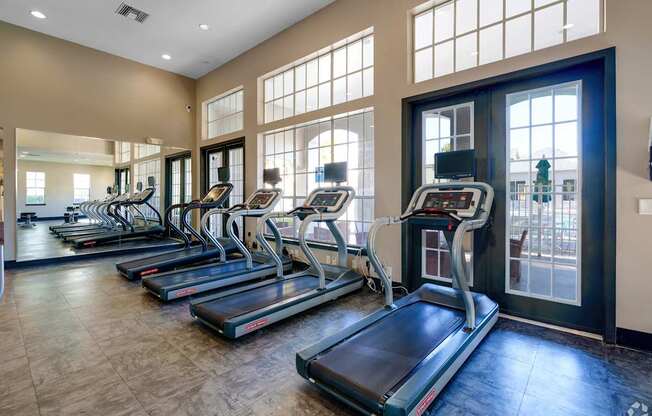 A gym with treadmills and a view of a city.