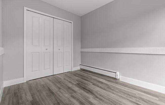 an empty room with wood flooring and white walls and doors