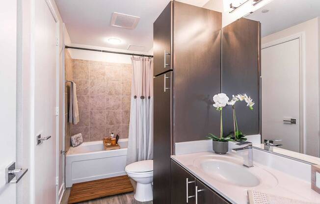 bathroom with espresso cabinets, white countertops and bath shower combo