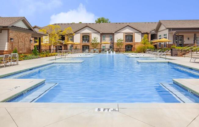 Well-maintained swimming pool and lounging chairs with parasols in One White Oak apartment rentals