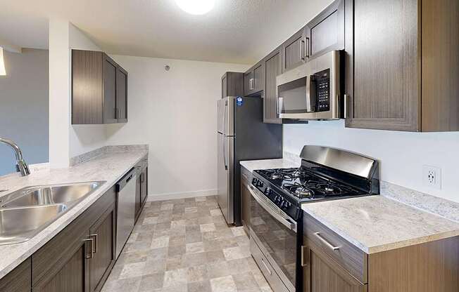 A kitchen with a stove, sink, and refrigerator at The Reserve at Destination Pointe apartments, Grimes, IA