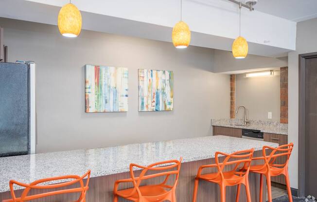 a kitchen with a long counter and orange chairs