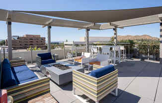 a rooftop patio with couches and chairs and a fire pit