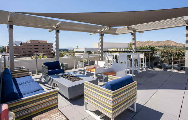 a rooftop patio with couches and chairs and a fire pit
