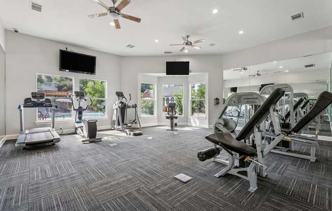 A spacious gym with a variety of equipment including treadmills, elliptical machines, and weight machines.