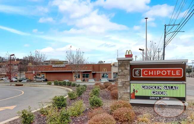 A restaurant with a sign for chipotle in front of a road