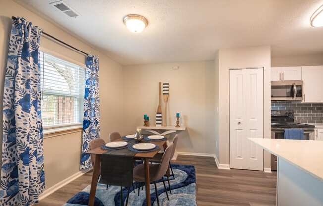 a dining area with a table and chairs and a kitchen in the background